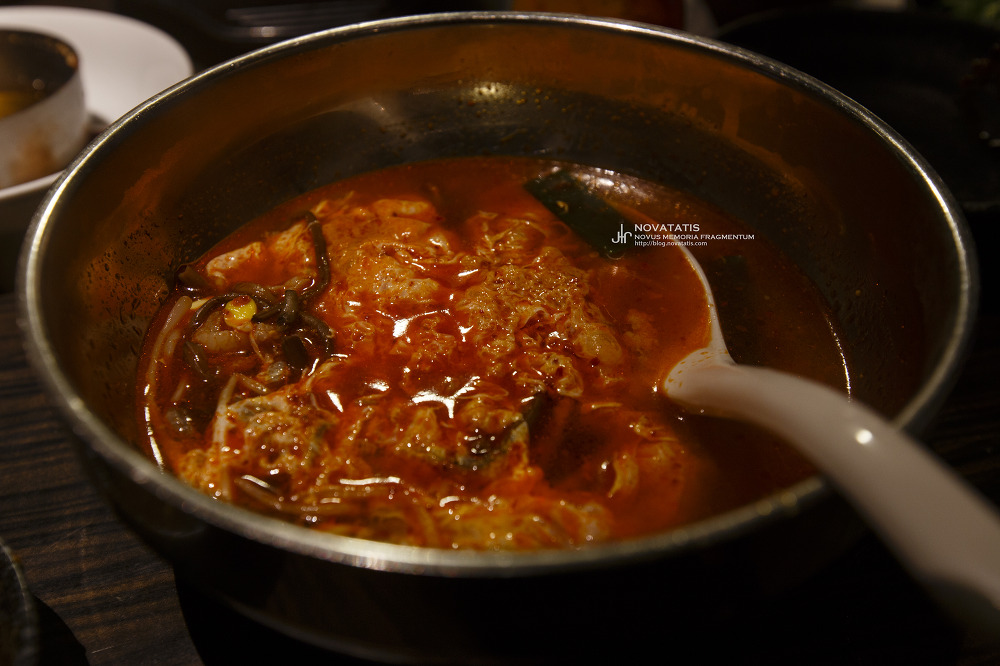 금속 그릇에 붉은 국물 찌개와 국자