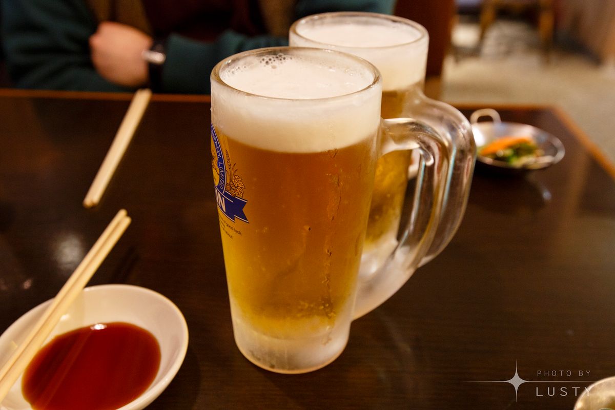 거품 있는 생맥주 잔 두 개와 젓가락