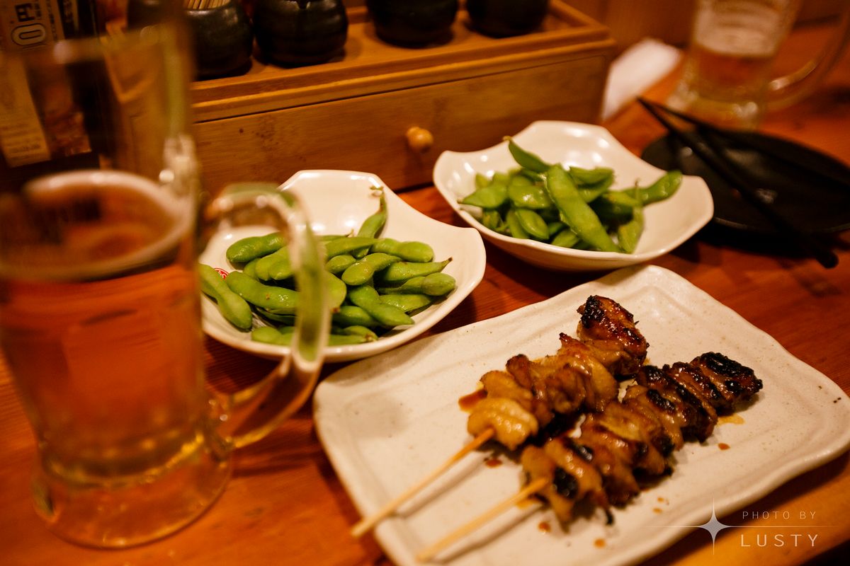 맥주잔과 에다마메, 꼬치가 놓인 테이블