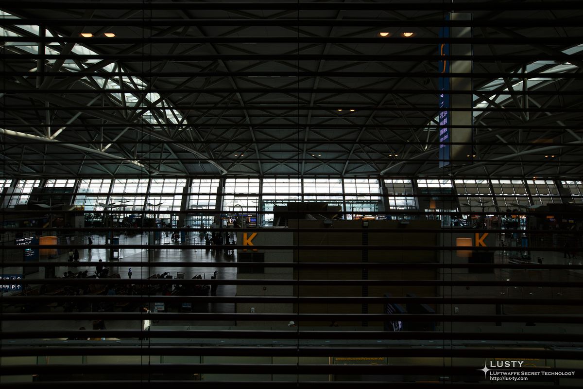 공항 대합실과 구조가 보이는 격자 창 너머 실내 전경
